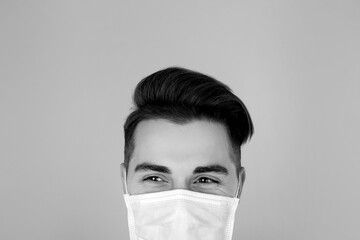 Man wearing medical face mask on light background. Black and white photography