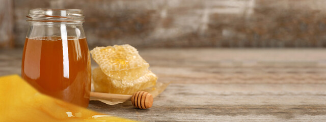 Jar of tasty fresh honey and dipper on table, space for text. Banner design