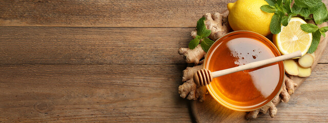 Tasty aromatic honey, lemon, ginger and mint on wooden table, top view with space for text. Banner...