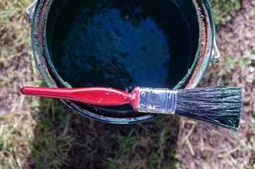 A paint brush waits for the painter to return from a break to continue painting the house.