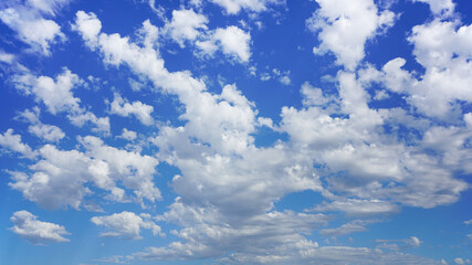 Naklejka na ściany i meble Beautiful puffy clouds under a sunny blue sky.