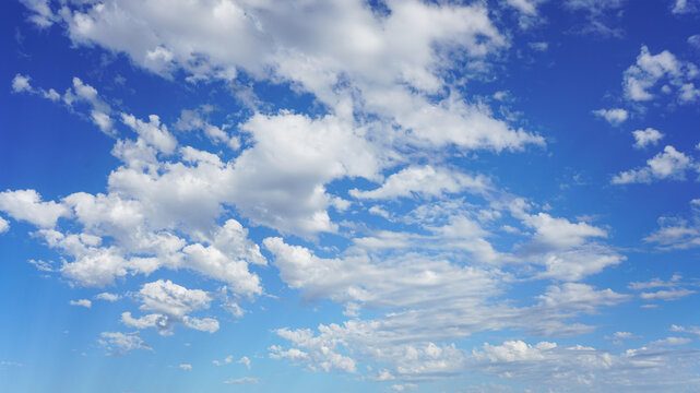 Puffy cumulus clouds under a sunny blue sky.