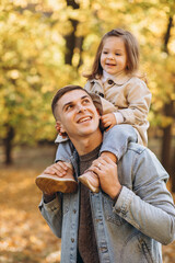Fototapeta premium Happy dad and little daughter walking in autumn park, father's day concept