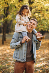 Happy dad and little daughter walking in autumn park, father's day concept