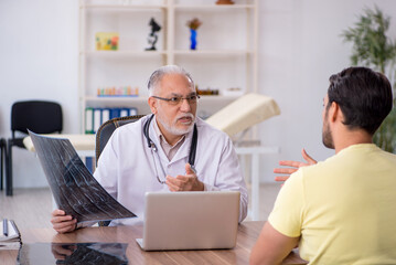 Young male doctor visiting old male doctor radiologist