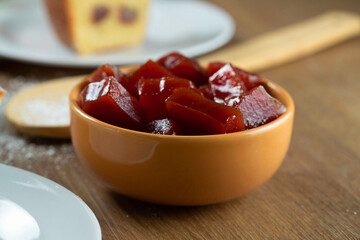 yellow can with guava jam cut into cubes with guavas in the background on wooden table