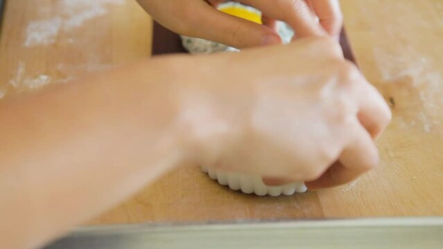 Woman uses a ravioli stam to remove excess pasta dough