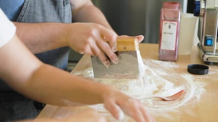 Man uses bench scraper to knead flour into pasta dough