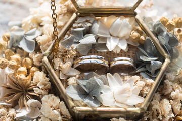 Golden wedding rings of the bride and groom with decorative glass box and flower. The wedding ring is decorated with flowers and a glass box for wedding rings. Wedding preparation holy 