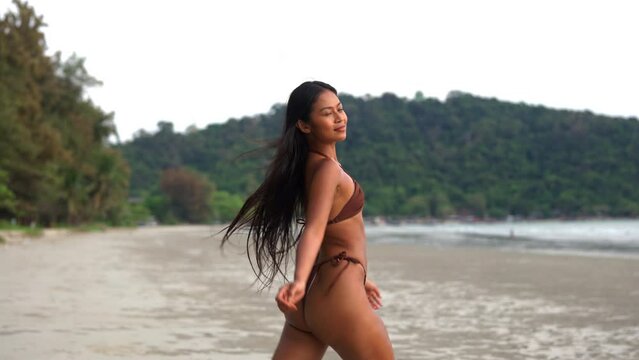 Beautiful Young Woman Walking Along Beach In Bikini