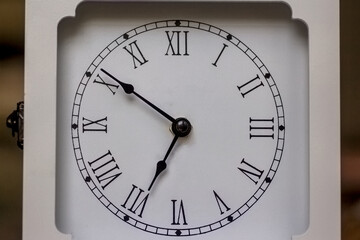 Square white analog clock showing 5:46 with a circular face with roman numerals