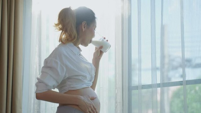 Asian beautiful pregnancy woman drink a glass of milk for health care.	