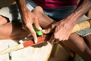 Hand of an indigenous person carving on the surface of the blowpipe or sumpit. 