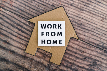 work from home sign with house icon made of cardboard over wooden background, digital nomads...