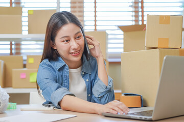 Small business entrepreneur SME, asian young woman owner packing product, checking parcel box delivery, using smartphone receive order from customer, working at home office. Merchant online, ecommerce