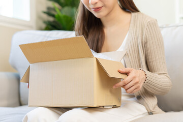 Happy asian young woman, girl customer sitting on sofa at home, hand in opening and unpacking...