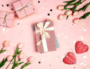 Gift books bandaged with a pink ribbon bow surrounded by tulips, confetti and hearts on pink...