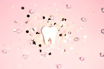 White tooth on a pink background with confetti and crystals.