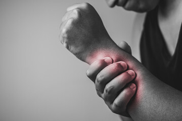 Elbow injury from tennis and golf. The man uses fingers to massage his arm. Pain symptom area is shown with red color. Healthcare knowledge. Medium close up shot with copy space. Black and white tone.
