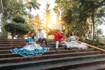 Teenagers from Latin America with traditional costumes doing a dab on the steps of a public park in...