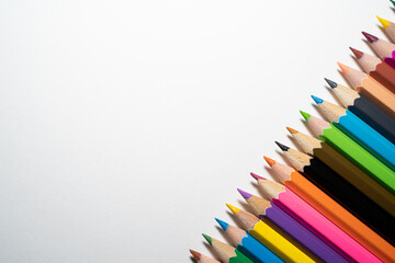 Sharpened colored pencils on the lower right corner of a white background