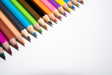 Colored pencils on the upper left corner on a white background