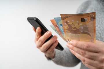 Young woman holds mobile phone and euro money in her hands