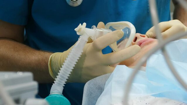 Little child under anaesthesia. Breathing mask on boy face. Health care and life saving. Breathing tube being inserted into mouth of kid. Preparing for surgery. Treatment of multiple caries. Operation