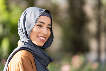 Portrait with copy space of a smiling muslim woman outdoors - obrazy, fototapety, plakaty