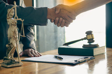 Businessmen shake hands with lawyers to seal a deal with a partner lawyer or a lawyer who is discussing a contract agreement. with a hammer and the goddess of justice