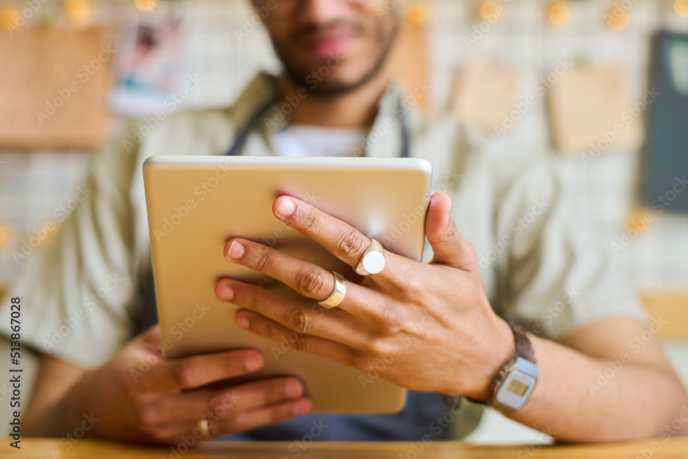 Poster Hands of young black man holding tablet in front of himself while networking and looking through online orders of clients