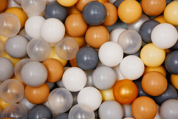 Colorful white, silver, gold and gray plastic balls for a dry pool as a background.
