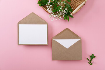 Blank greeting cards and envelopes with gypsophila on pink background. Blank paper sheet cards with...