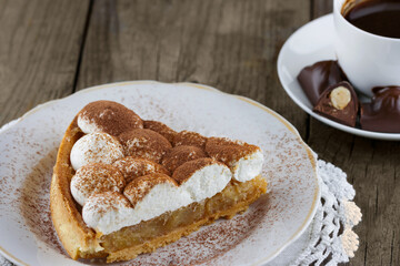 Piece of cake with cream on a plate and a cup of coffee