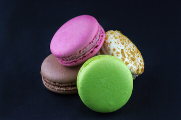 A bunch of colorful macaroons on a black background.