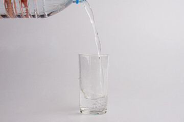 Close up pouring purified fresh drink water from the bottle isolated on white background