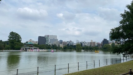 Obraz premium The moss green water pond at downtown Ueno Tokyo Japan, with beautiful clouds and skylines. Year 2022 June 22nd