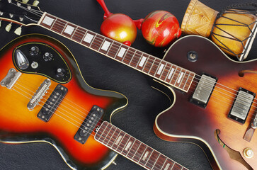 Fototapeta na wymiar Two jazz electric guitars, maracas, jembe on a dark background. Close up.