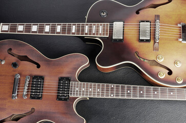 Naklejka na ściany i meble Two jazz electric guitars on a dark background. Close up.