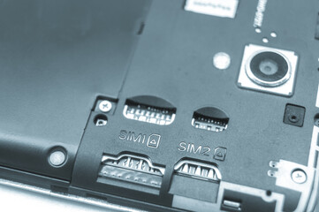 Obraz premium Slots for two SIM cards in a smartphone with an open back cover. Empty SIM slots. Blue tint. Selective focus