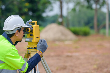 Male civil engineer surveying with theodolite apparatus Before construction on the construction site of roads or buildings with construction machinery background - Powered by Adobe