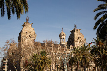 Fototapeta na wymiar Buildings and large palm trees along the popular tourist walking route, Passeig de Lluís Companys