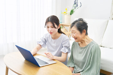 Obraz premium リビングでノートパソコンを使う孫と祖母
