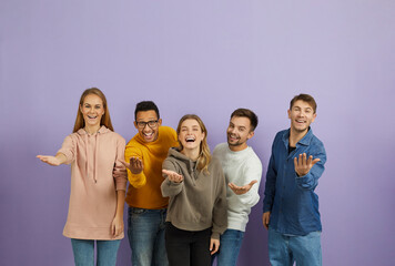 Diverse group of happy cheerful young multiethnic people standing together, looking at the camera, smiling, extending their hands and doing an inviting gesture, telling you 'Come here and join us'