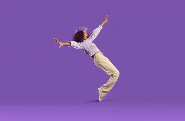 Fototapeten Cheerful joyful african american teenage girl having fun getting on her toes on purple background. Funny stylish preteen girl fooling around, rejoicing and laughing out loud. Full height. Banner. © Studio Romantic