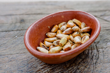 Toasted Andean corn with salt served on a rustic bowl, on a wooden table. Peruvian food