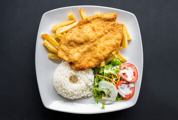 Milanese fried chicken cutlet with salad, French fries and rice. Top View