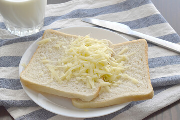 Grated cheese on bread.  Cheese sandwich on a white plate. 