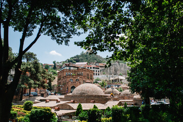Fototapeta na wymiar Sulfur baths in the old town in Tbilisi. Georgian houses against the background of the fortress Narikala. City landscape. Georgia.