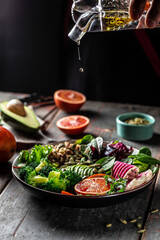 vegetable vegetarian buddha bowl avocado, blood orange, broccoli, watermelon radish, spinach, quinoa, pumpkin seeds. vertical image, place for text